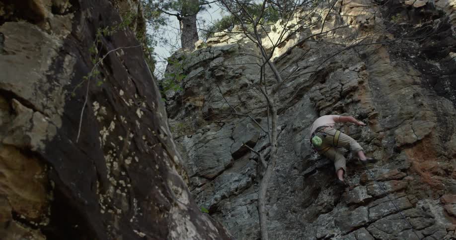 A man climbs up the side of a rock mountain