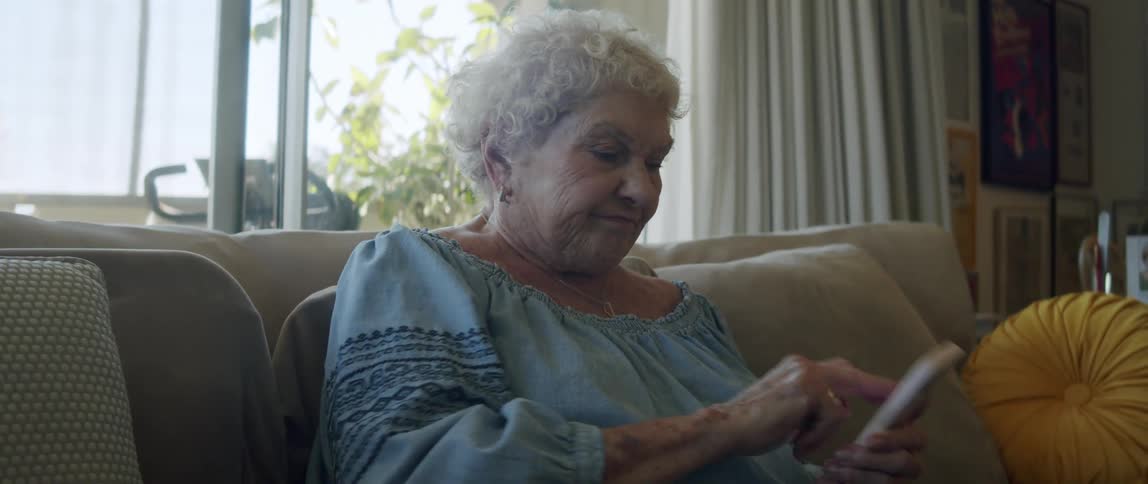 Elderly lady sitting and a little irritated while using her smartphone
