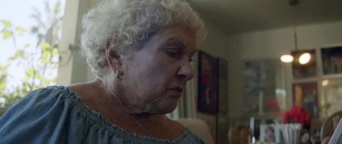 Elderly lady sitting in living room interacting with her smartphone