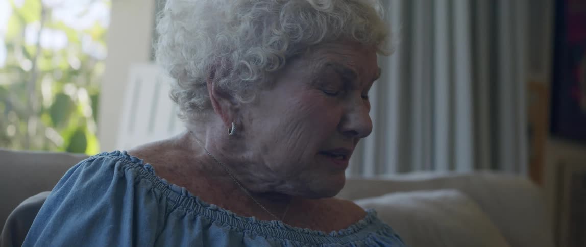 An elderly woman reading on her smartphone sitting on the couch at home