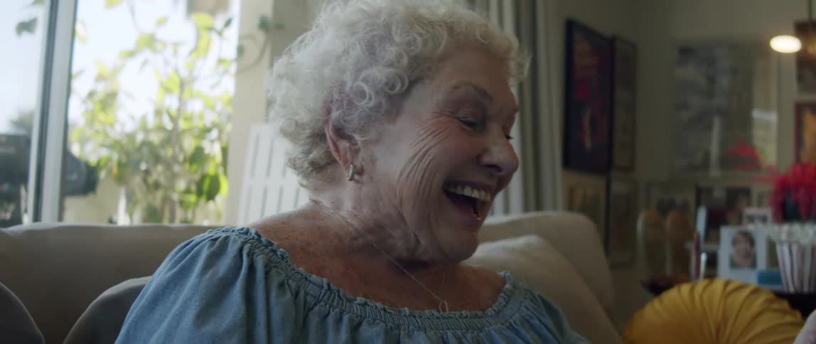 A senior woman laughs while looking at her phone