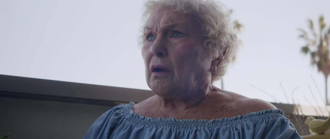 The old woman reading the newspaper looks up startled and stares off into the distance in thought