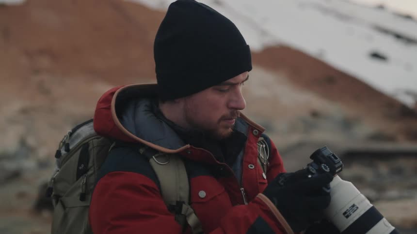A photographer takes pictures of a barren snow covered mountain range