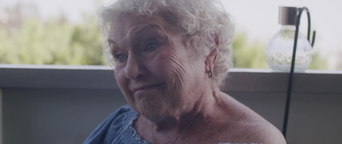 Elderly woman sitting reading newspaper