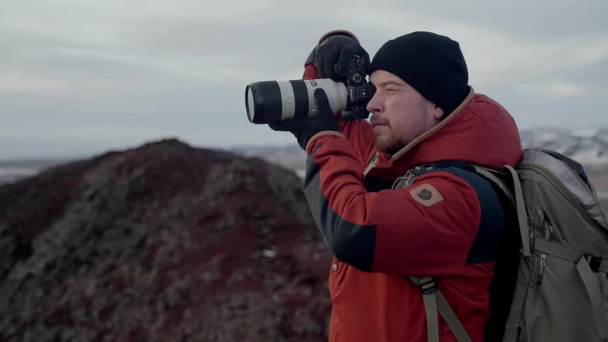 A photographer takes pictures of a barren mountain range