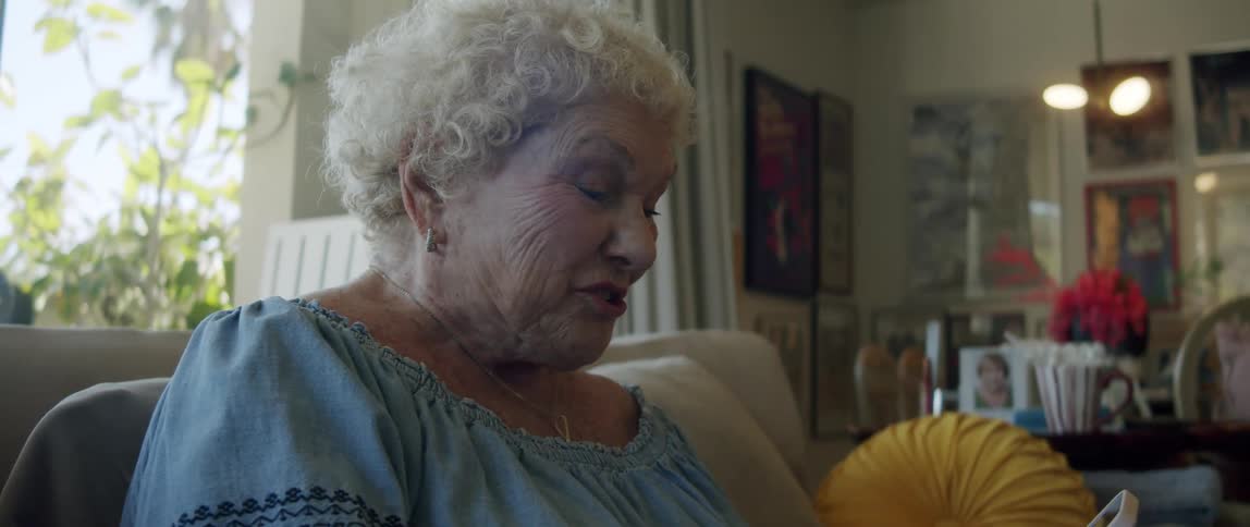 Elderly woman sitting in living room using smartphone