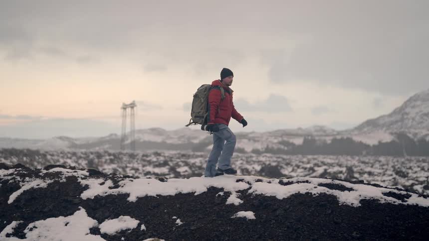 Man with a professional camera walking on a snowy mountain on a misty morning