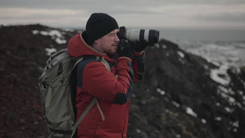 Professional photographer using his camera in a natural environment on a snowy mountain