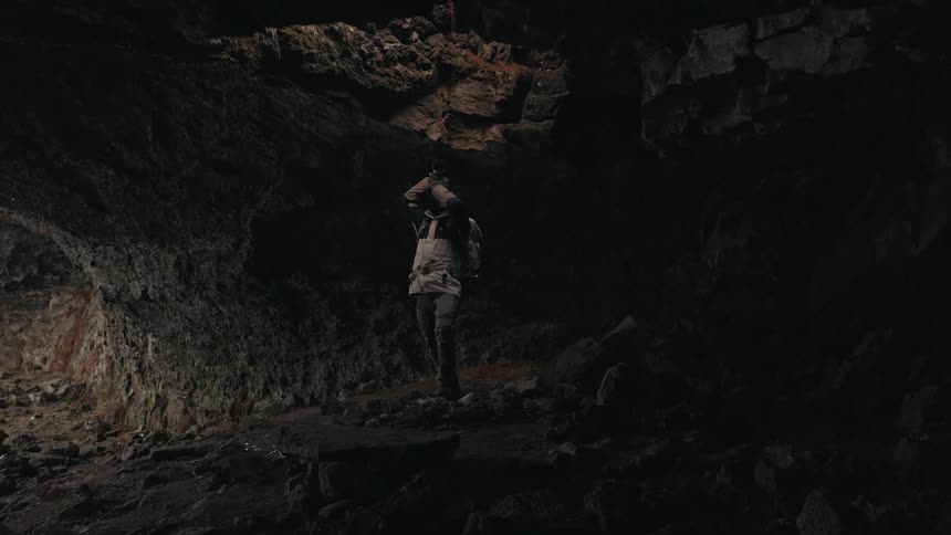 Man with a professional camera pointing it up inside a cave into a hole