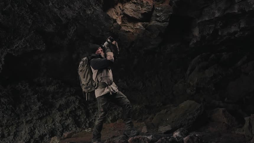 Photographer exploring a cave and taking pictures with a professional camera