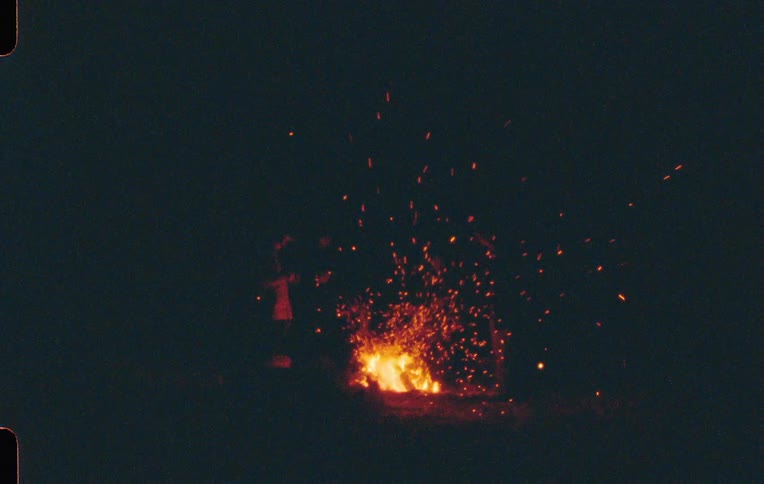 Silhouette of people around a campfire at night