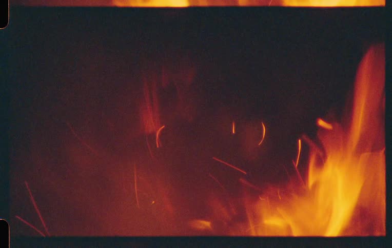 Glowing embers float in a dark smokefilled space above dancing flames
