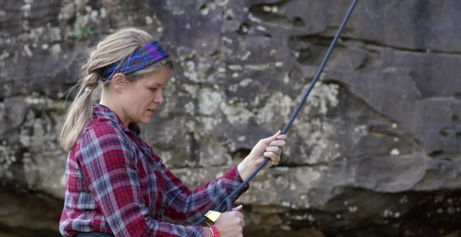 Woman holding onto a rope next to a cliff