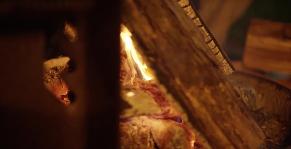A fire is blazing between splits of wood