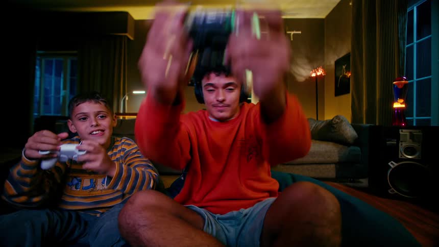 Two brothers are sitting in their living room while playing a video game