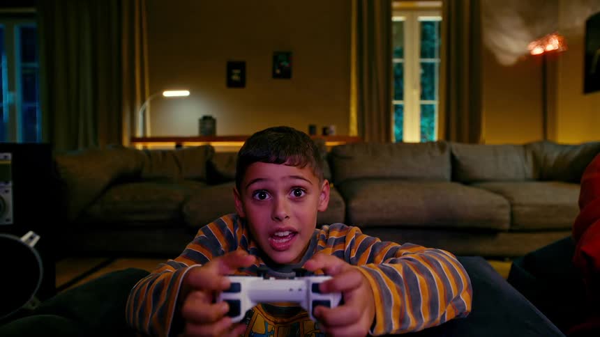 Little boy sitting and cheering while playing video games in the living room