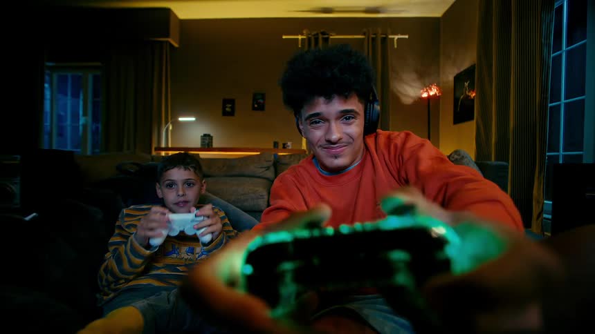Teenage girl and a boy playing video games together in the living room at night