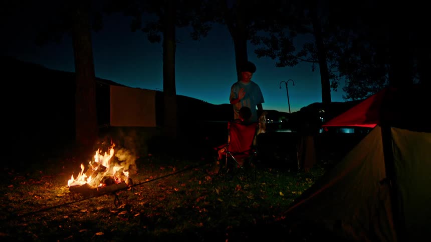 Two brothers high five next to a fire at a campsite