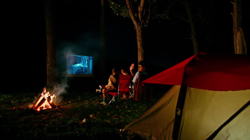 Two brothers watch television outside at a camping site