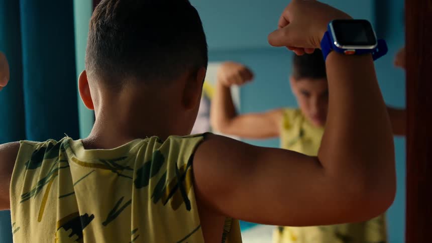 A clip of a boy looking at the mirror while assessing his biceps