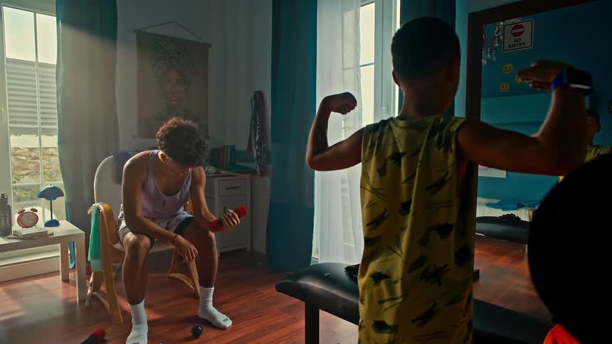 Boy showing off his double biceps to a teenager using a dumbbell