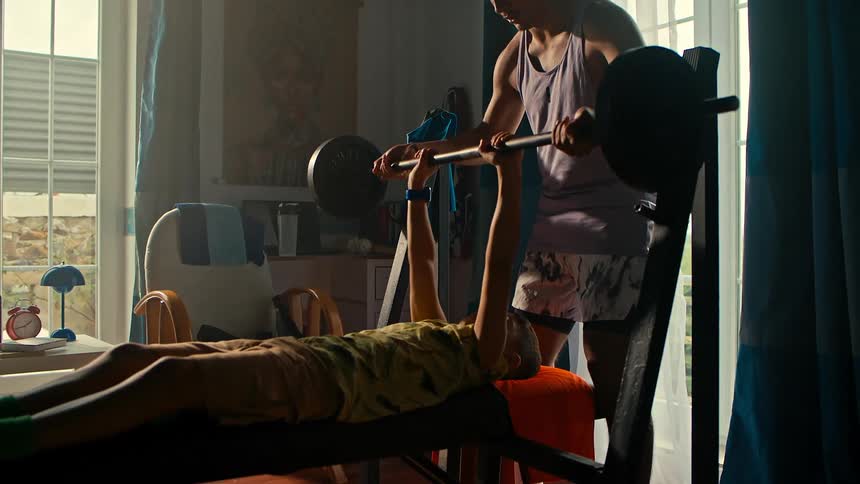 Teenager helping a boy do bench press
