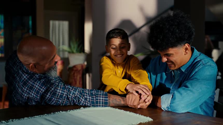 Father arm wrestling with older son and younger brother comes and helps father