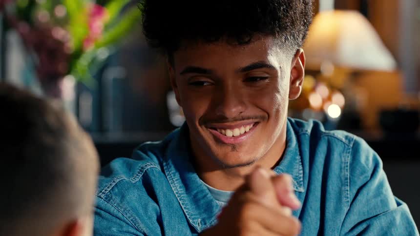 The face of a young man smiling who is arm wrestling with a child and then he leaves and the man is left without a smile on his face