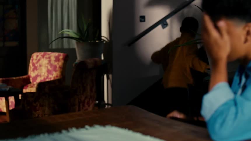Two boys one older and one younger are arm wrestling and the one who loses leaves the place and goes up the stairs
