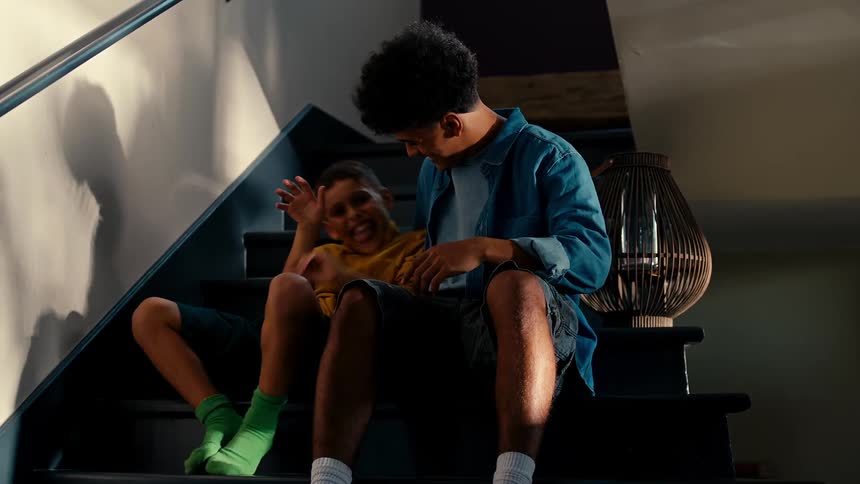 Teenager sitting next to his friend who is looking downcast and then becomes happy