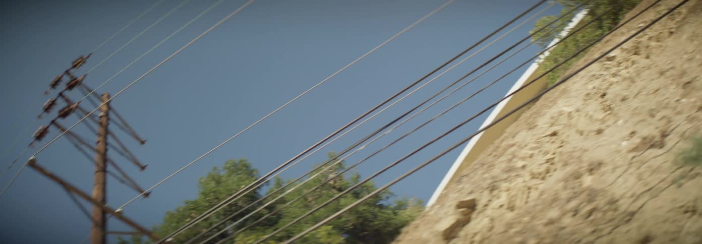 Power lines parallel a fence at the base of a hill on a summer day