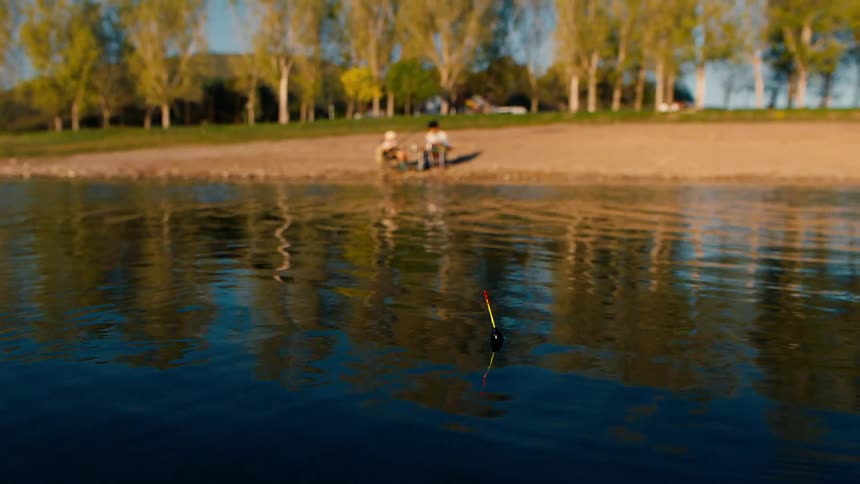 Two people are fishing in the lake by the forest