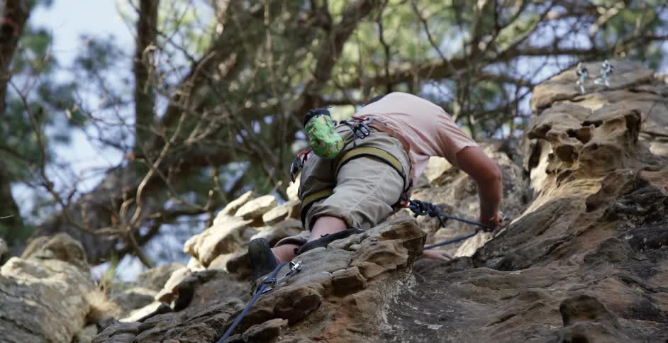 Rock climber adjusting his equipment on his assent