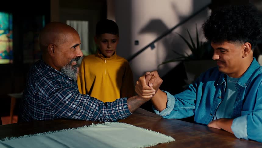Father and son in an arm wrestling match and the youngest helping his father