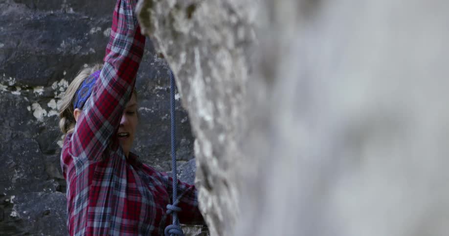A woman using a harness and rock climbing