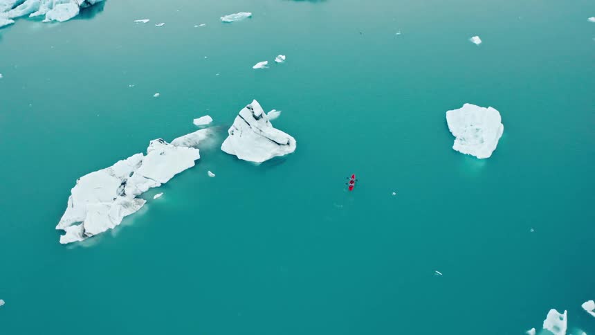 Kayaking between icebergs in blue ocean waters in the arctic
