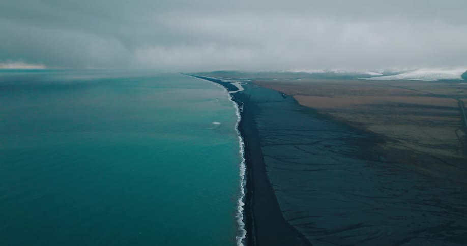 Aerial landscape of a blue ocean meeting a volcanic land on a cloudy day