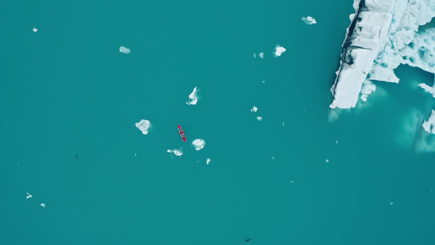 Aerial view of a kayak in an ocean with icebergs