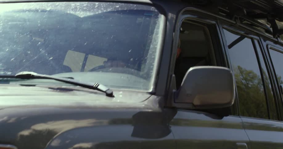 A man is driving an suv during the day