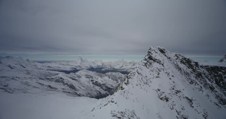 A snowcapped mountain peak stands tall against a muted sky