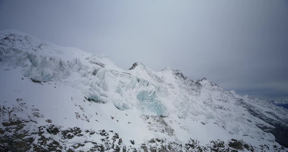 A desolate snowcapped mountain range stretches towards the horizon shrouded in a thick layer of fog