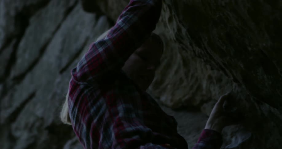 A woman climbs down a rock face