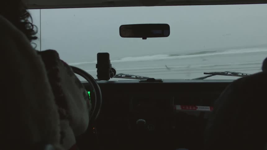 People drive on a beach on a foggy day