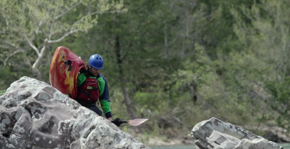 A man is carrying a kayak to the river