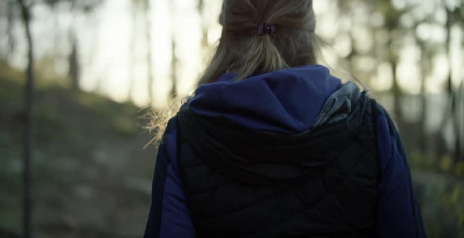 A man and a woman are walking down a woodland trail