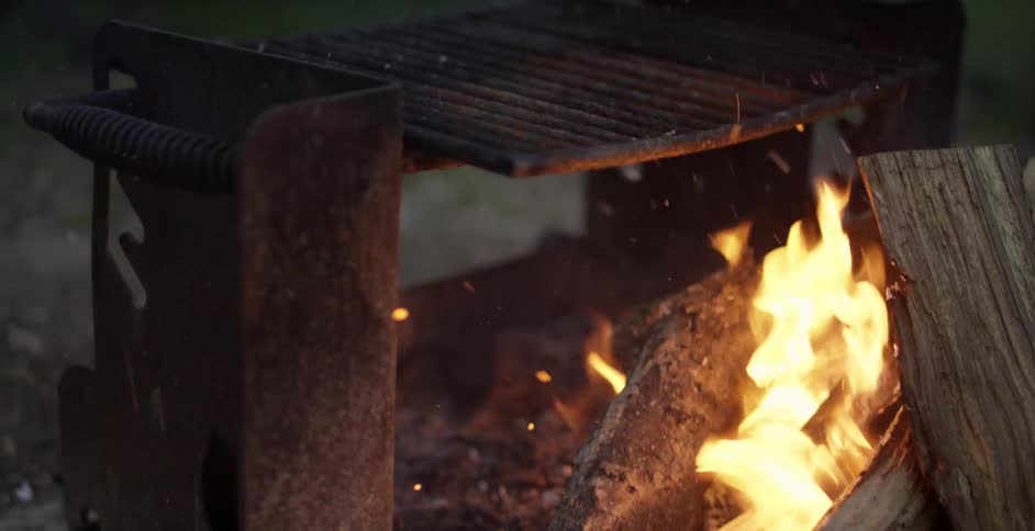 Logs flame and burn under a grill grate
