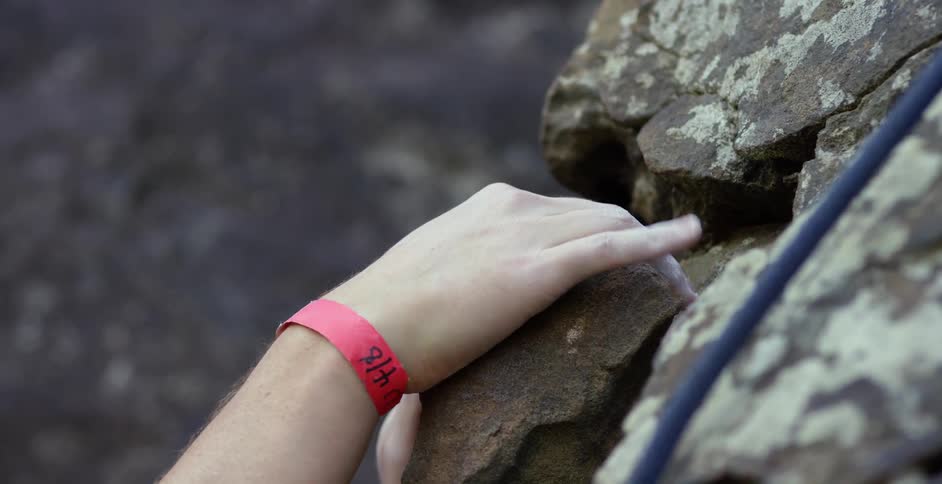 A rock climber's hand grabs a rock