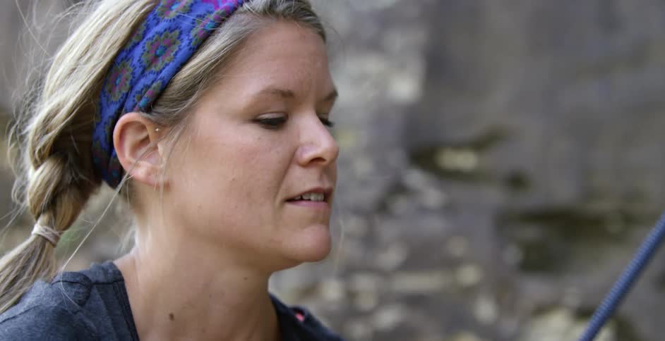 Woman rock climber adjusting her rope as she looks upward