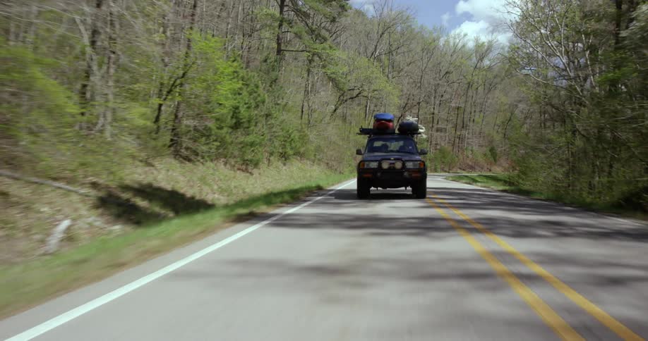 Vehicle loaded with equipment on top driving down a paved road