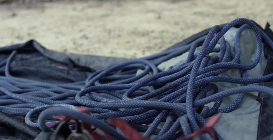 Someone is grabbing some blue rope that is laying on the ground